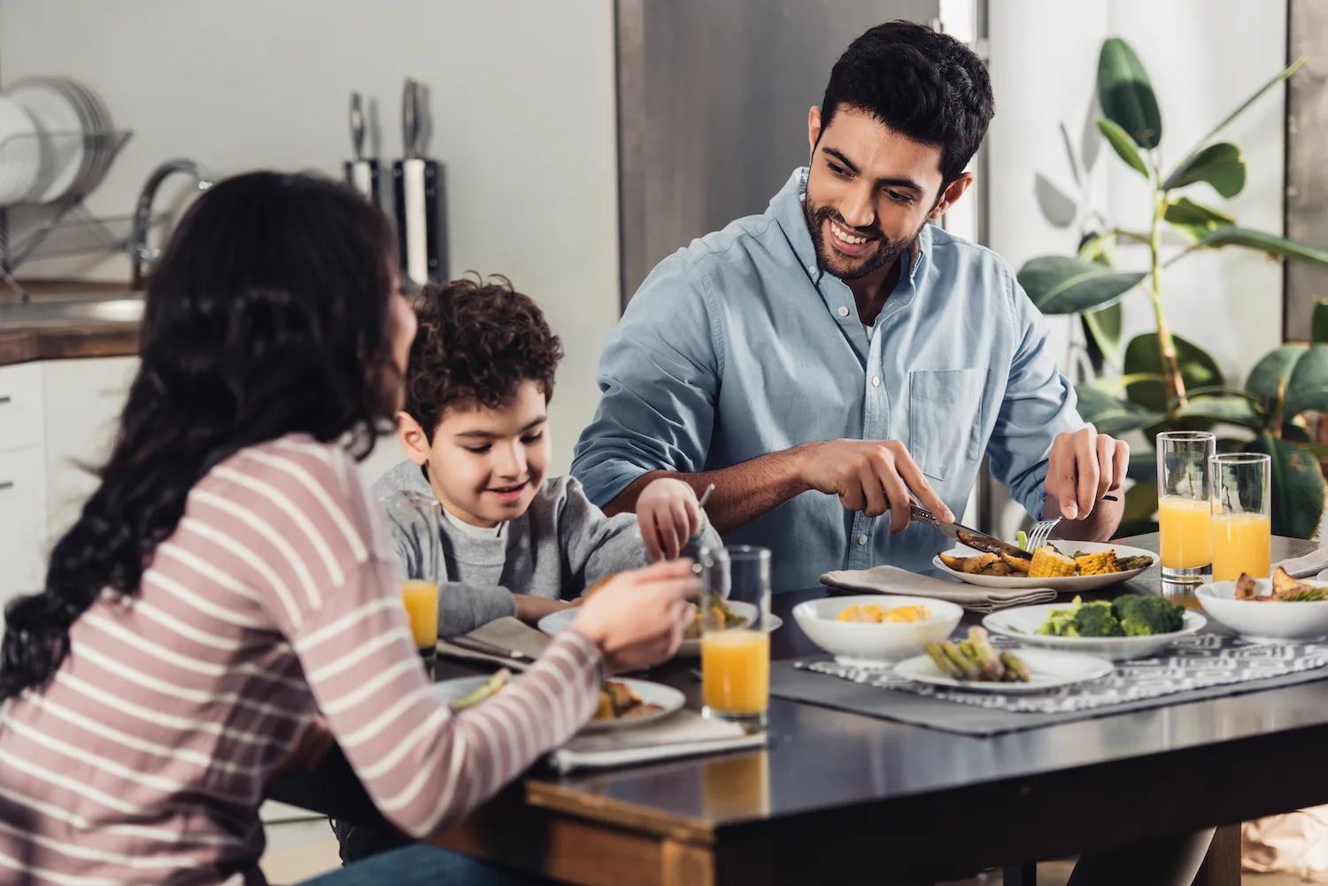 Familia disfrutando de comida con verduras y cítricos.
