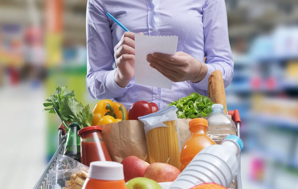 Persona revisando su lista de compras y productos con actitud relajada y organizada.
